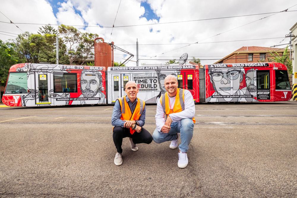 Photo: Time to ReBuild's podcast hosts pose in front of the YMCA ReBuild tram.