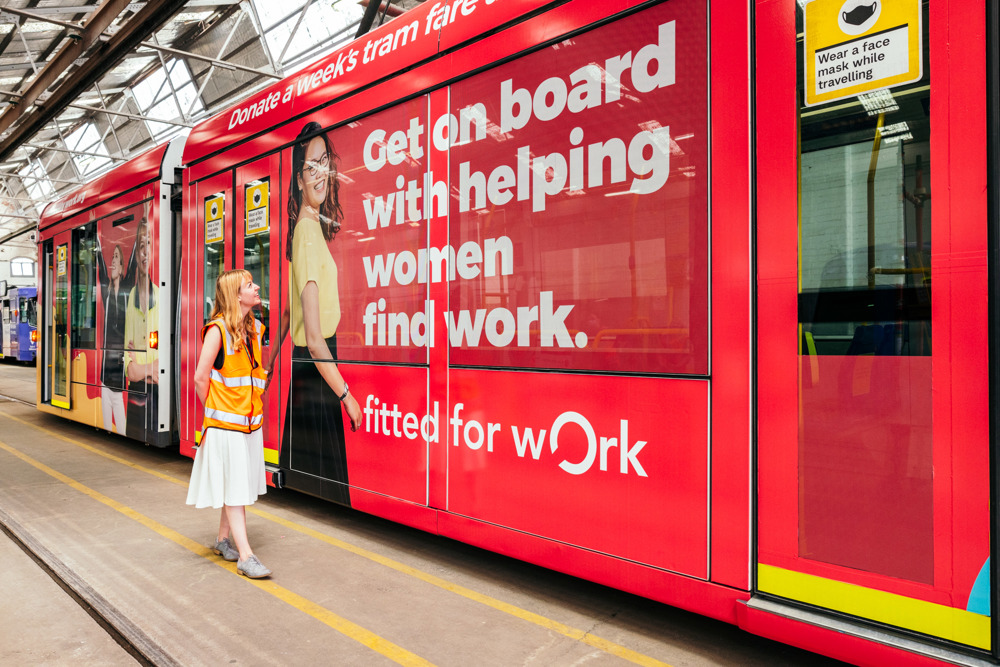 Photo: A Fitted For Work employee poses with their in-kind advertising tram.