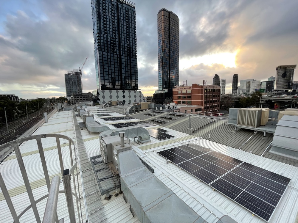 Photo of a tram depot's roof with solar panels, large office buildings in the background
